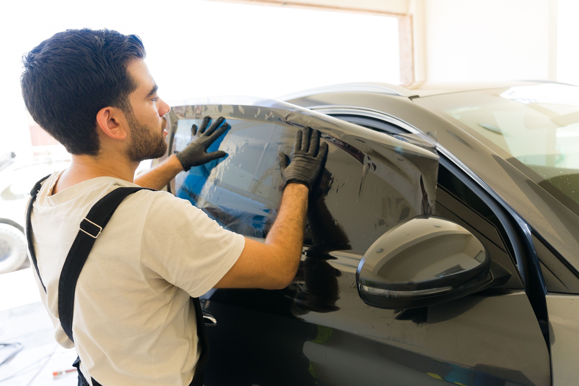 Male specialist applying car tinting film